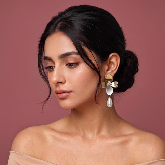 Gold plated floral drop earrings with sparkling center stone and white pearl drop worn by a woman