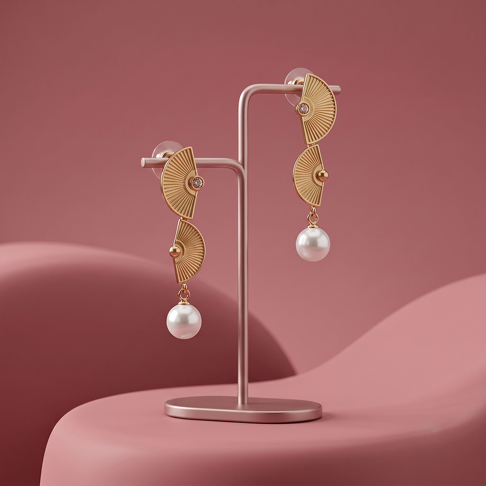 Gold plated fan shaped drop earrings with crystal accents and white pearl drop displayed on a jewelry stand