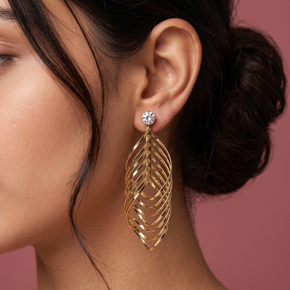 Gold plated leaf inspired drop earrings with sparkling crystal stud and layered curved design worn by a woman