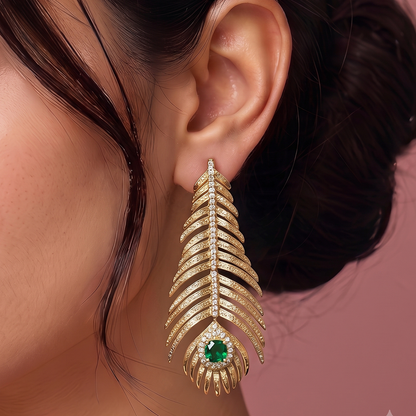 Close-up of gold plated leaf inspired drop earring with crystal accents and green gemstone detail