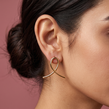 Gold plated statement loop drop earrings with elegant curved design worn by a woman