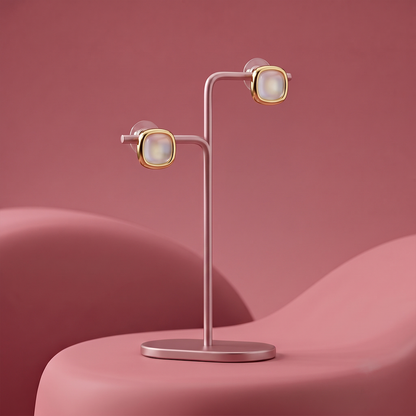 Gold plated square stud earrings with white pearl center displayed on a jewelry stand