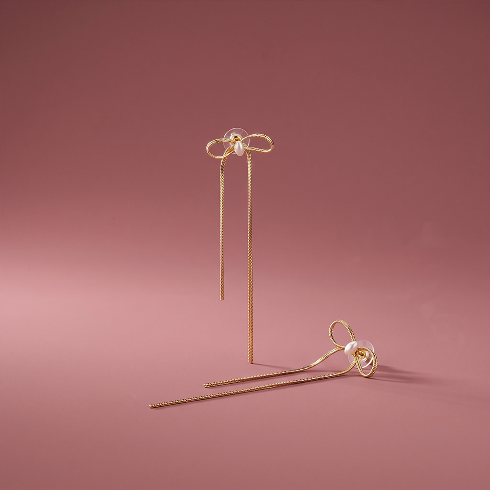 Gold plated bow drop stud earrings with pearl accent and uneven hanging chains