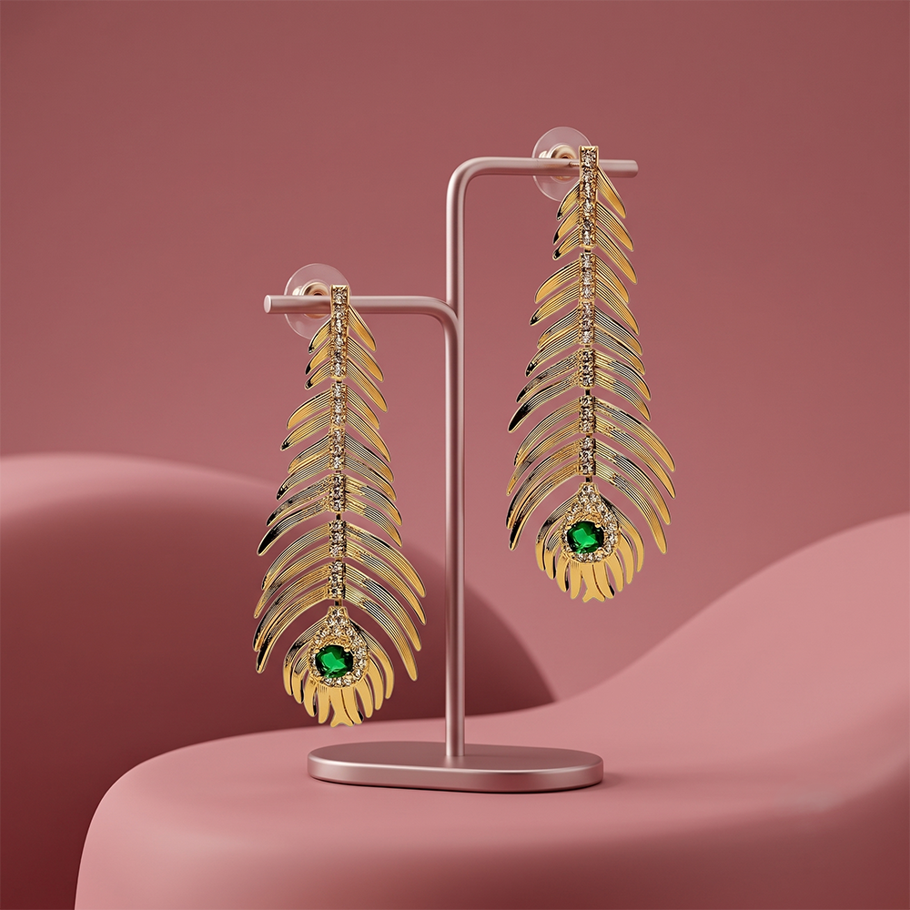 Gold plated leaf drop earrings with crystal detailing and green gemstone displayed on a jewelry stand