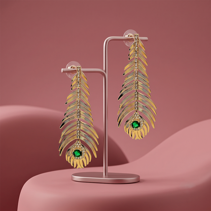 Gold plated leaf drop earrings with crystal detailing and green gemstone displayed on a jewelry stand